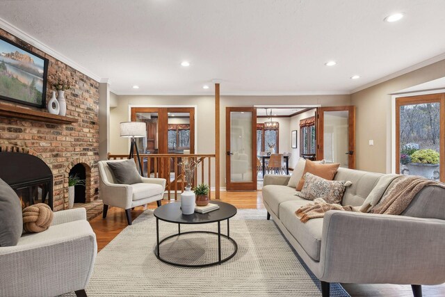 living room featuring crown molding, hardwood / wood-style floors, french doors, and a brick fireplace