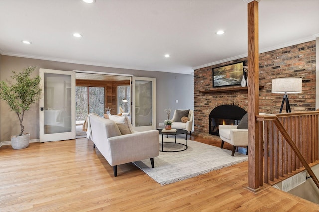 living room featuring crown molding, light hardwood / wood-style floors, and a brick fireplace