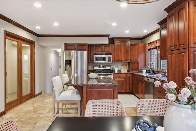 kitchen with crown molding, sink, dark stone countertops, a kitchen island, and stainless steel appliances