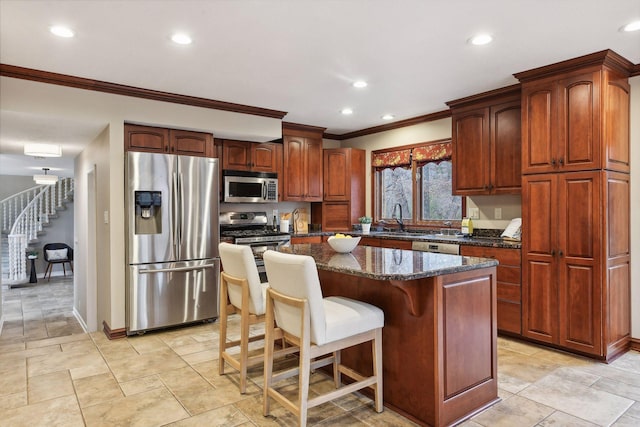 kitchen with sink, crown molding, dark stone countertops, appliances with stainless steel finishes, and a kitchen island