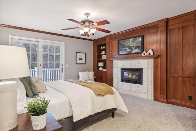 bedroom with access to exterior, ceiling fan, a tile fireplace, dark colored carpet, and crown molding