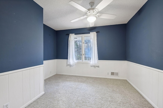 spare room featuring light carpet, a textured ceiling, and ceiling fan