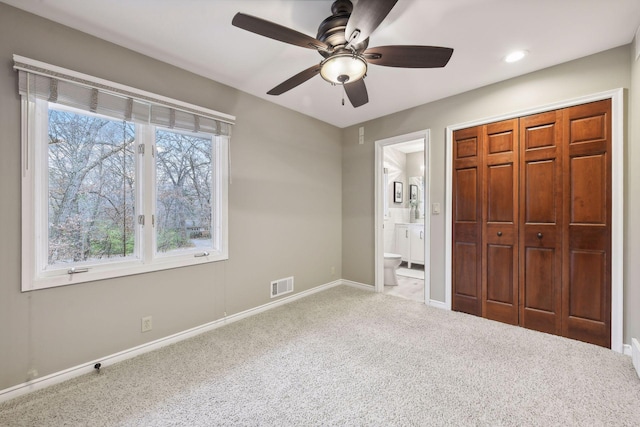 unfurnished bedroom with ensuite bathroom, ceiling fan, light carpet, and a closet