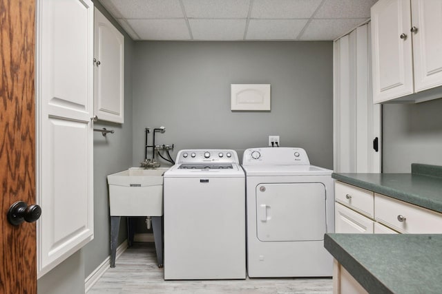 laundry room with washer and dryer, cabinets, and light wood-type flooring