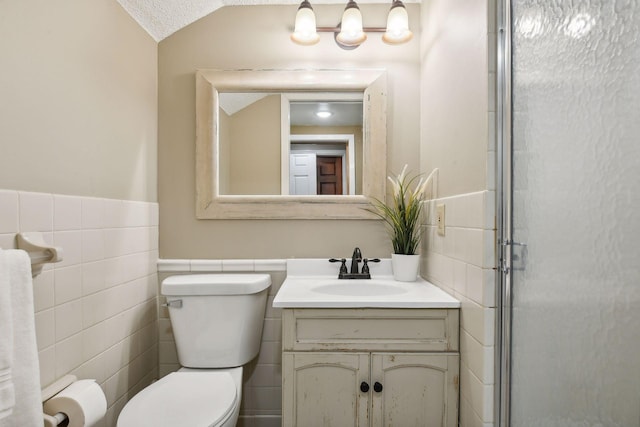 bathroom featuring a textured ceiling, vanity, vaulted ceiling, tile walls, and toilet