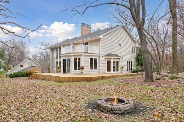 back of house featuring a balcony, an outdoor fire pit, and french doors