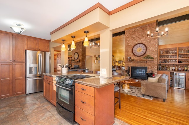 kitchen featuring a kitchen breakfast bar, stainless steel fridge, black range with electric cooktop, decorative light fixtures, and light stone counters