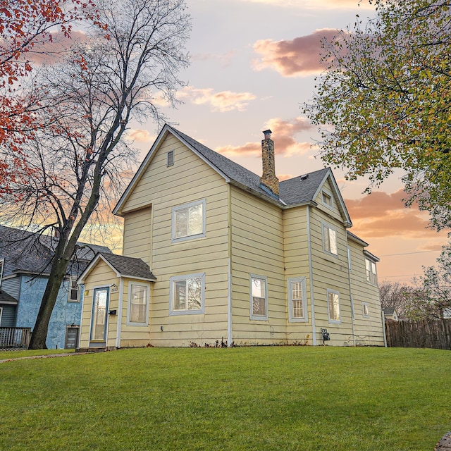 back house at dusk featuring a yard