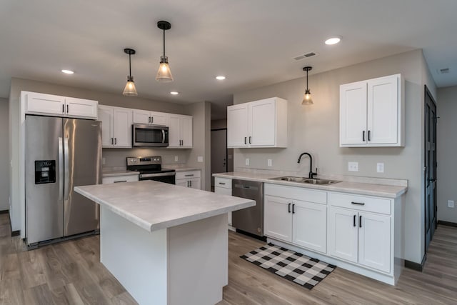 kitchen featuring light wood finished floors, light countertops, stainless steel appliances, white cabinetry, and a sink