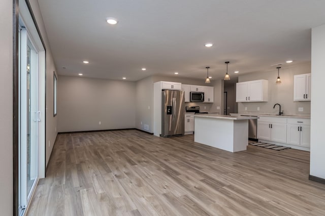 kitchen with a sink, appliances with stainless steel finishes, light wood-style flooring, and light countertops