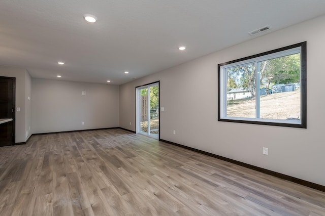 unfurnished room featuring light wood-type flooring, visible vents, baseboards, and recessed lighting