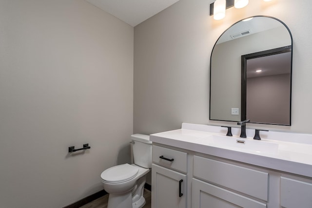 bathroom with vanity, toilet, and visible vents