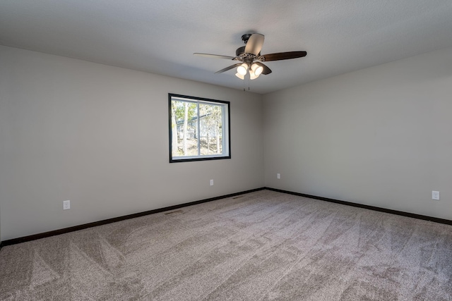 carpeted empty room featuring visible vents, baseboards, and ceiling fan