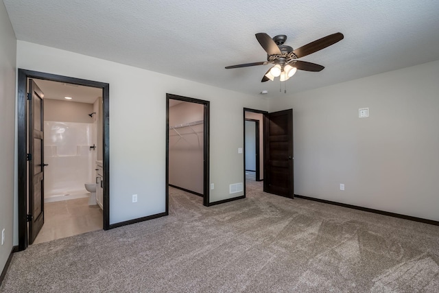 unfurnished bedroom featuring a spacious closet, light colored carpet, visible vents, and a textured ceiling