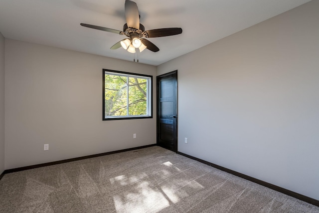 carpeted empty room with a ceiling fan and baseboards