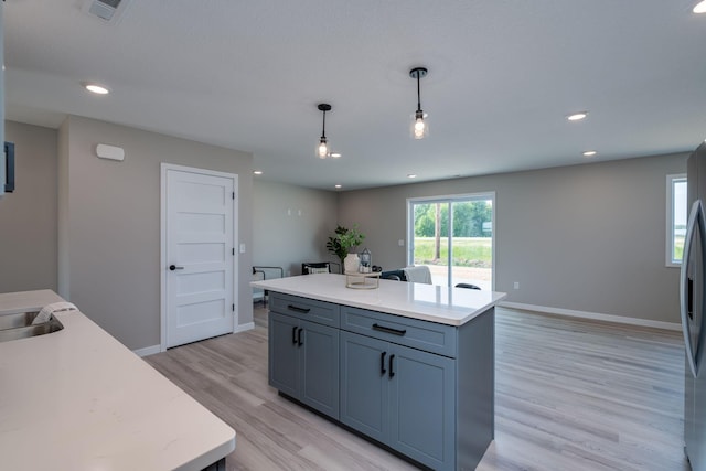 3104 Scotch Ln, Mankato, MN 56001 - kitchen featuring light countertops, a kitchen island, decorative light fixtures, light wood-style flooring, and baseboards