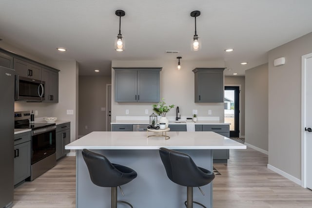3104 Scotch Ln, Mankato, MN 56001 - kitchen with appliances with stainless steel finishes, light countertops, a kitchen island, a kitchen bar, and light wood-style floors