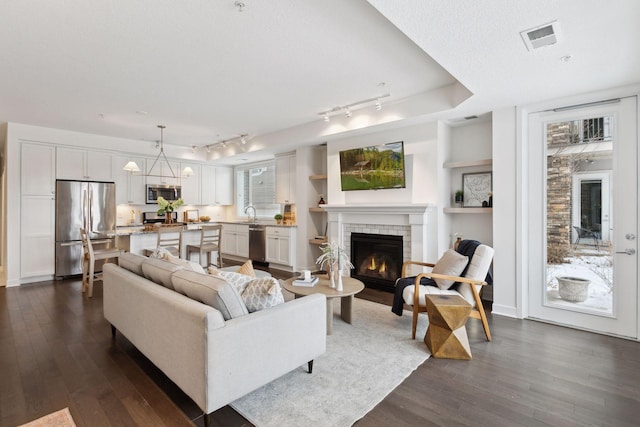 living room featuring dark hardwood / wood-style flooring, a textured ceiling, and a fireplace