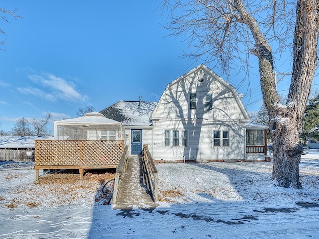 snow covered house featuring a sunroom and a deck