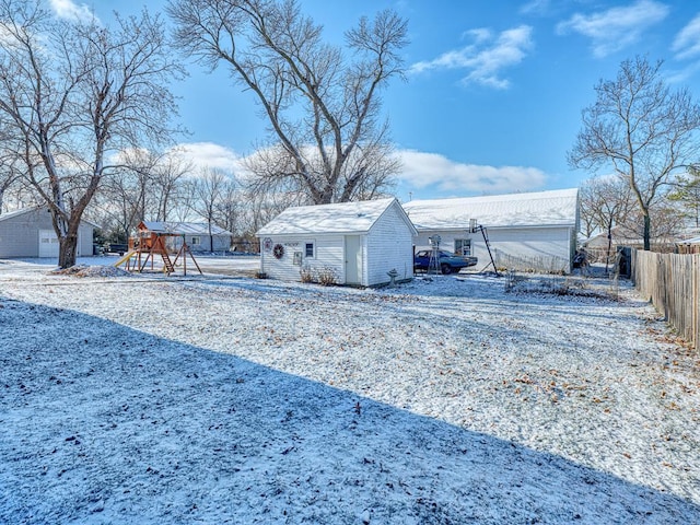 yard covered in snow with a playground and an outdoor structure