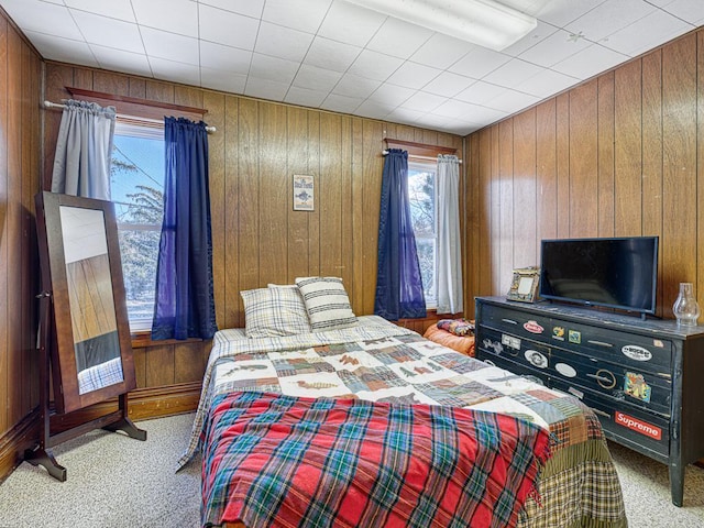 carpeted bedroom featuring wood walls