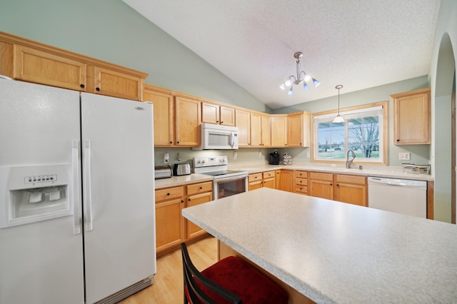 kitchen with a notable chandelier, pendant lighting, vaulted ceiling, white appliances, and light hardwood / wood-style floors