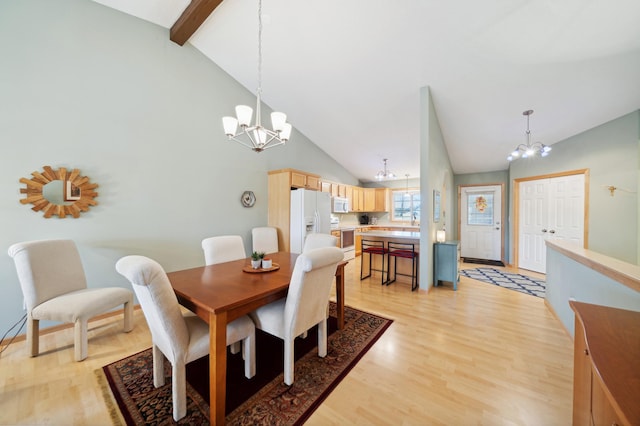 dining area featuring sink, light hardwood / wood-style flooring, an inviting chandelier, high vaulted ceiling, and beamed ceiling