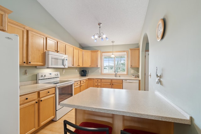 kitchen with lofted ceiling, light countertops, a textured ceiling, white appliances, and a kitchen breakfast bar