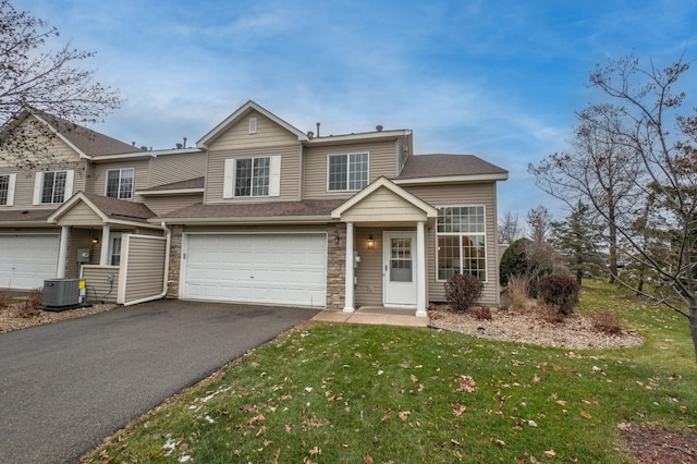 view of front of property featuring a front yard, central AC, and a garage