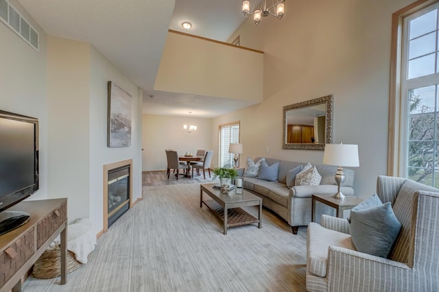 living room featuring high vaulted ceiling, light hardwood / wood-style floors, and an inviting chandelier