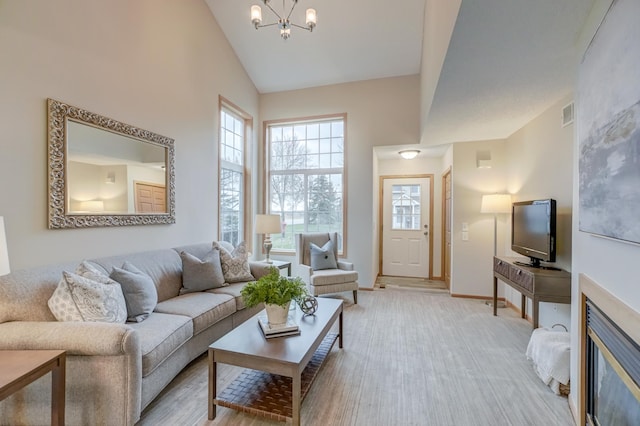 living room with a chandelier, high vaulted ceiling, and light hardwood / wood-style flooring