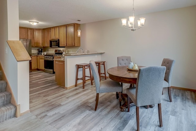 dining room with a textured ceiling, light hardwood / wood-style floors, an inviting chandelier, and sink