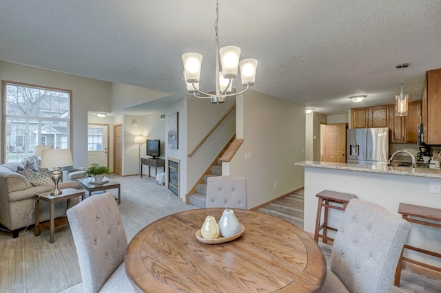 dining room featuring light hardwood / wood-style flooring, a chandelier, a textured ceiling, and sink