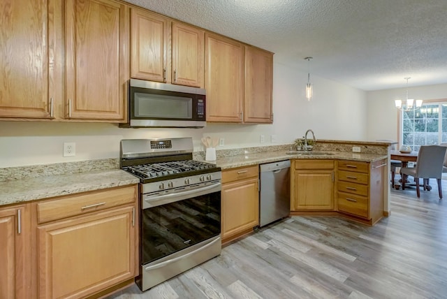 kitchen with pendant lighting, sink, light hardwood / wood-style flooring, a notable chandelier, and stainless steel appliances