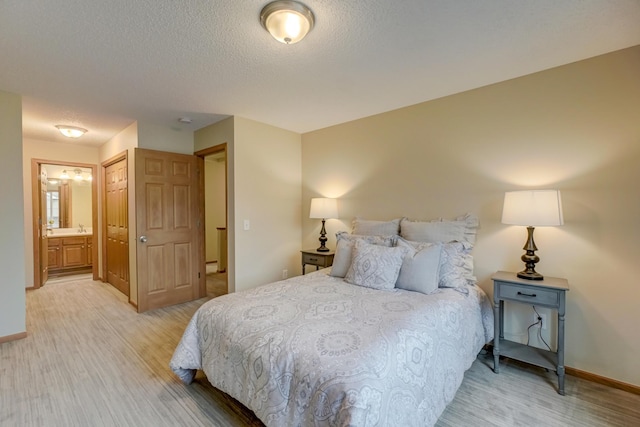 bedroom with a textured ceiling, light hardwood / wood-style flooring, and ensuite bath