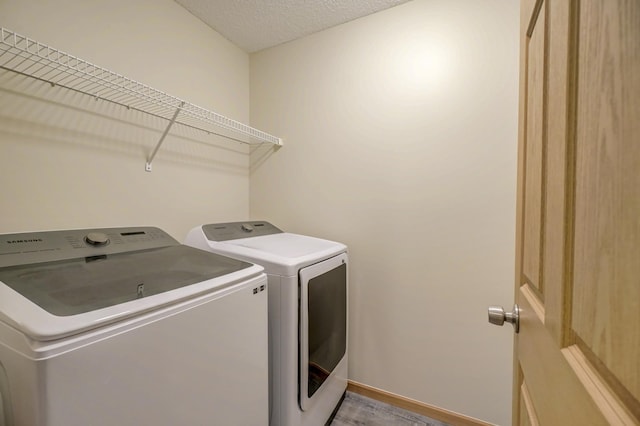 clothes washing area with independent washer and dryer and light hardwood / wood-style flooring