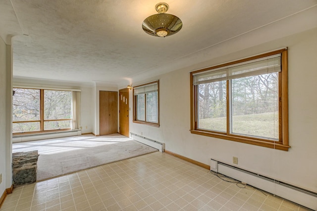 empty room featuring plenty of natural light and baseboard heating