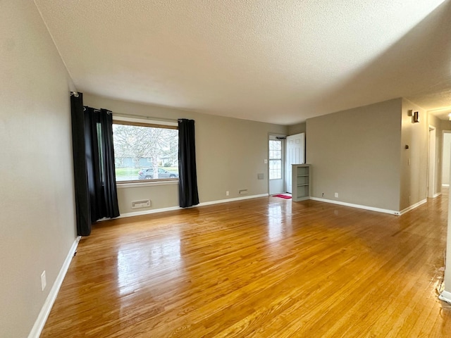 unfurnished room featuring a textured ceiling and light hardwood / wood-style flooring