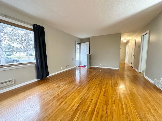 spare room with a textured ceiling and light hardwood / wood-style floors