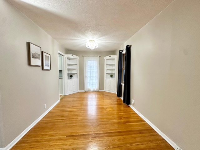 hallway featuring hardwood / wood-style floors, a textured ceiling, and a notable chandelier