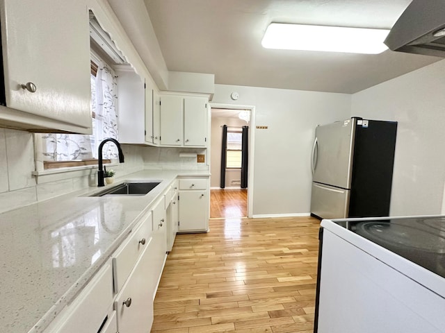 kitchen with sink, range, light hardwood / wood-style floors, white cabinetry, and stainless steel refrigerator