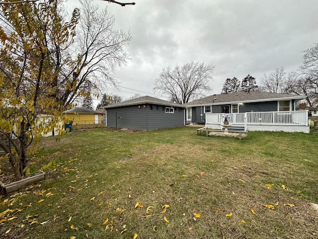 back of property with a wooden deck, a yard, and an outbuilding