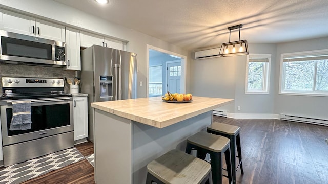 kitchen with wood counters, a breakfast bar, white cabinetry, a kitchen island, and stainless steel appliances