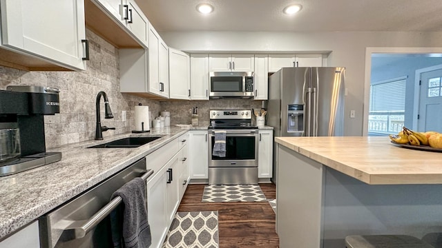 kitchen featuring butcher block countertops, white cabinetry, sink, stainless steel appliances, and dark wood-type flooring