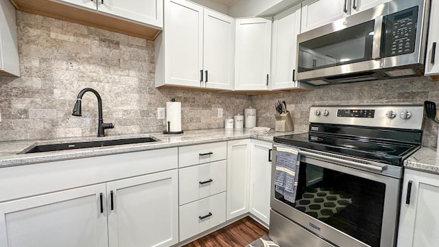 kitchen featuring sink, backsplash, stainless steel appliances, light stone counters, and white cabinets