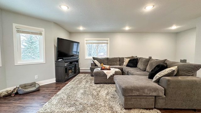 living room featuring baseboard heating, dark hardwood / wood-style flooring, and a textured ceiling