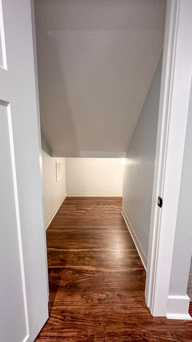 interior space featuring vaulted ceiling, hardwood / wood-style floors, and a textured ceiling