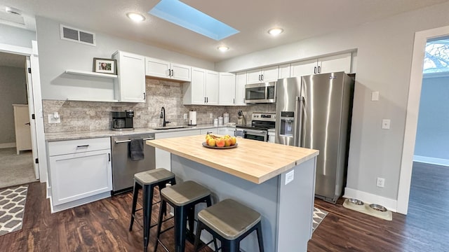 kitchen featuring sink, a breakfast bar, appliances with stainless steel finishes, a center island, and white cabinets