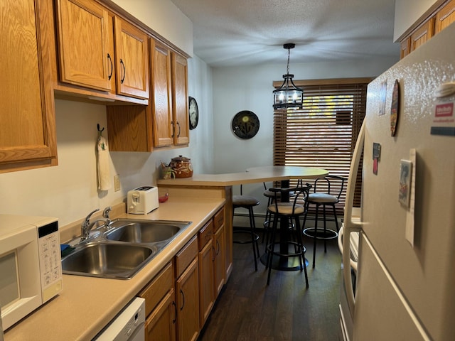 kitchen featuring white appliances, sink, decorative light fixtures, a notable chandelier, and dark hardwood / wood-style floors