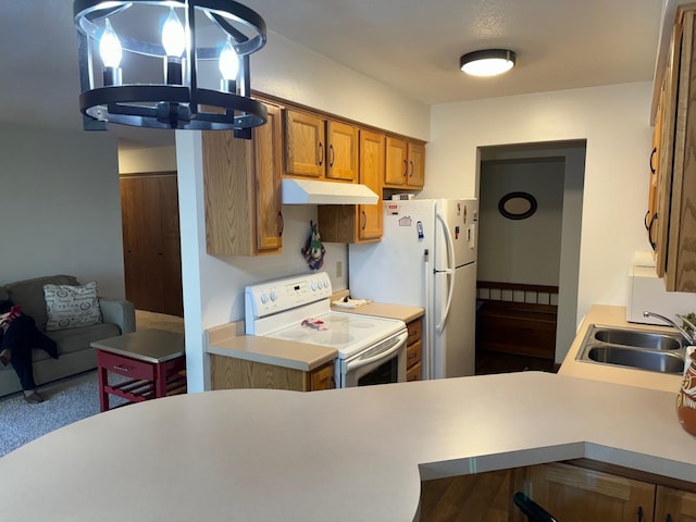 kitchen with white appliances, sink, hanging light fixtures, kitchen peninsula, and a chandelier